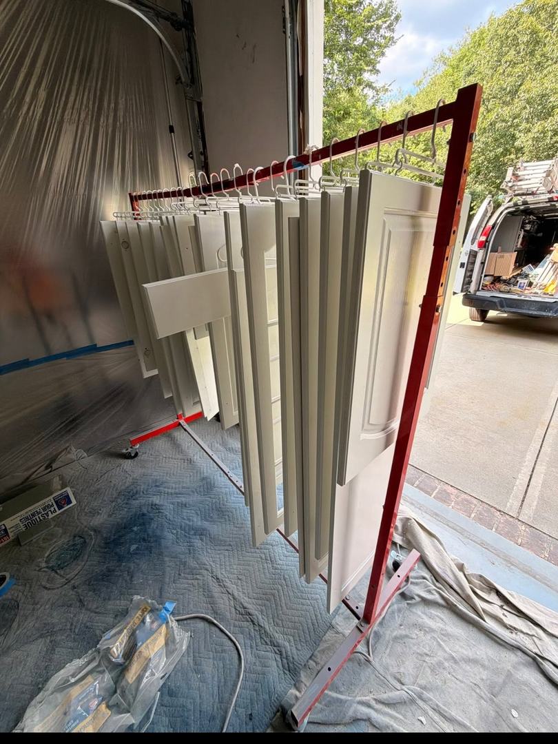 Kitchen Cabinet Painting – In Progress 2 Painted cabinet doors hanging on a drying rack during spray finishing